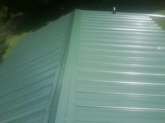 New green metal panels meeting at the ridge of a roof — Flat Roof Repair work by our crew in Smicksburg