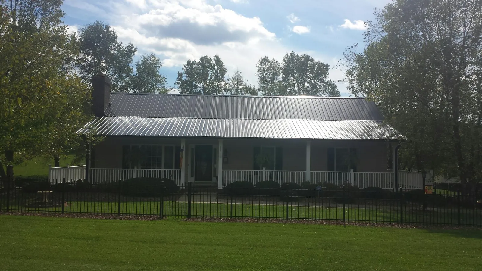 Gray metal roof on a brick ranch with a full width front porch — Gutter Guard Installation work by our crew in Smicksburg
