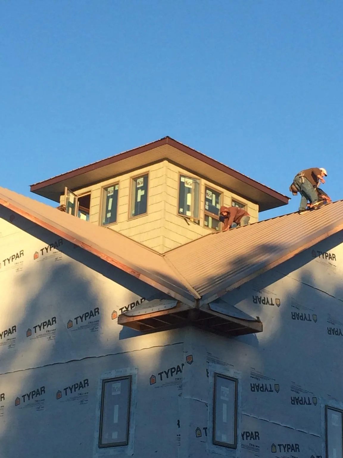 Roofers working around a rooftop cupola on a new metal roof at sunset — Roof Waterproofing in Smicksburg by Roofing Brothers